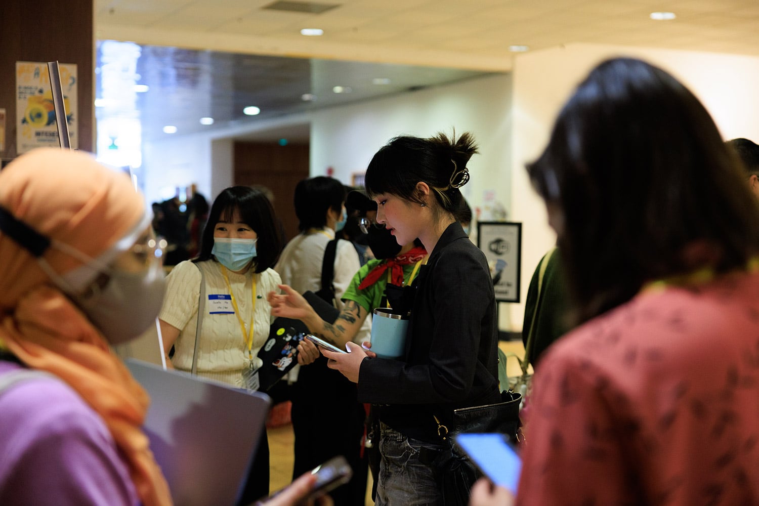 People talk and check their devices during a networking event.