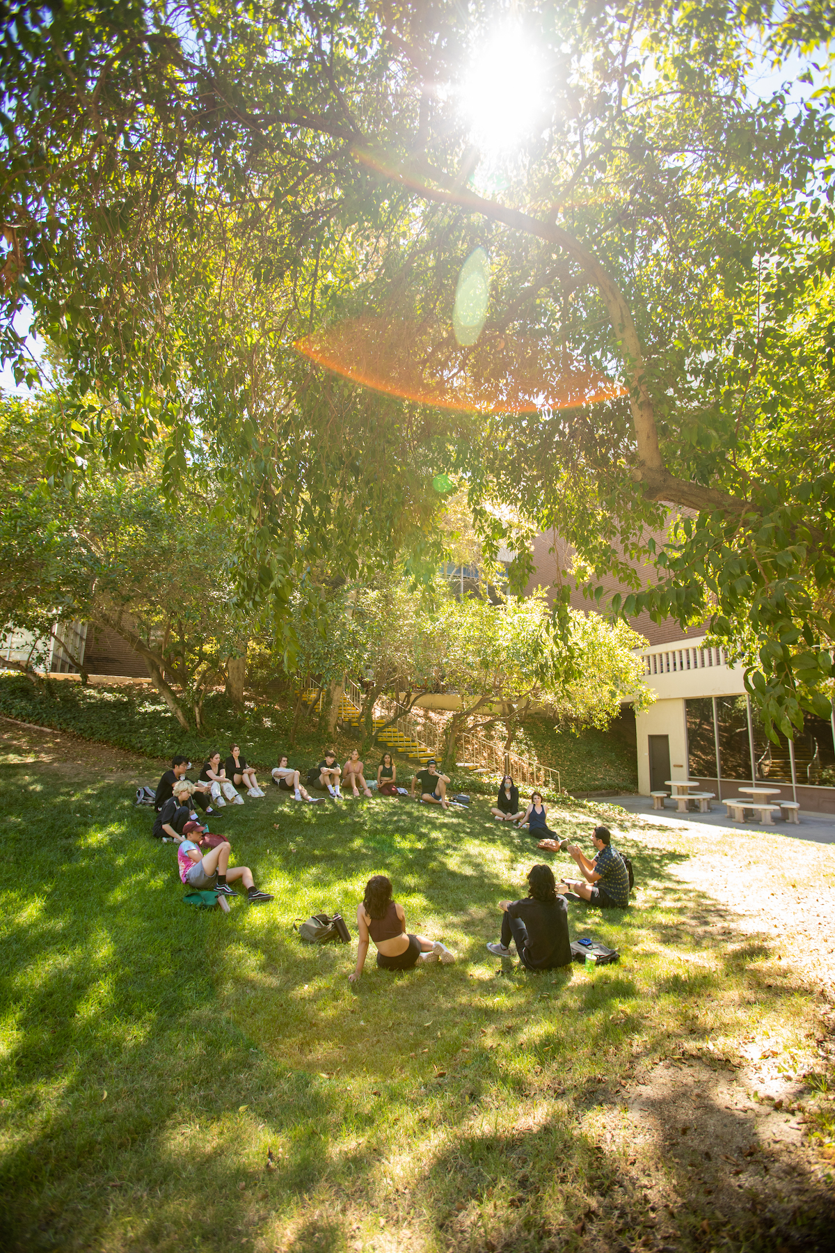 Students sitting in a circle outside at CalArts in the Lulu von Hagen courtyard on a sunny day