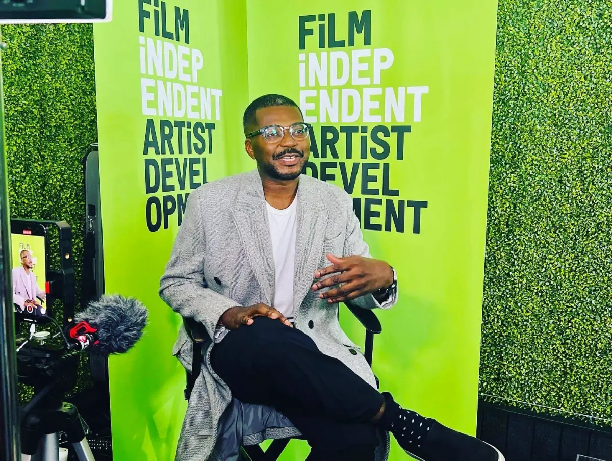 Filmmaker Mason Richards being interviewed in front of a bright green wall that reads “Film Independent Artist Development”