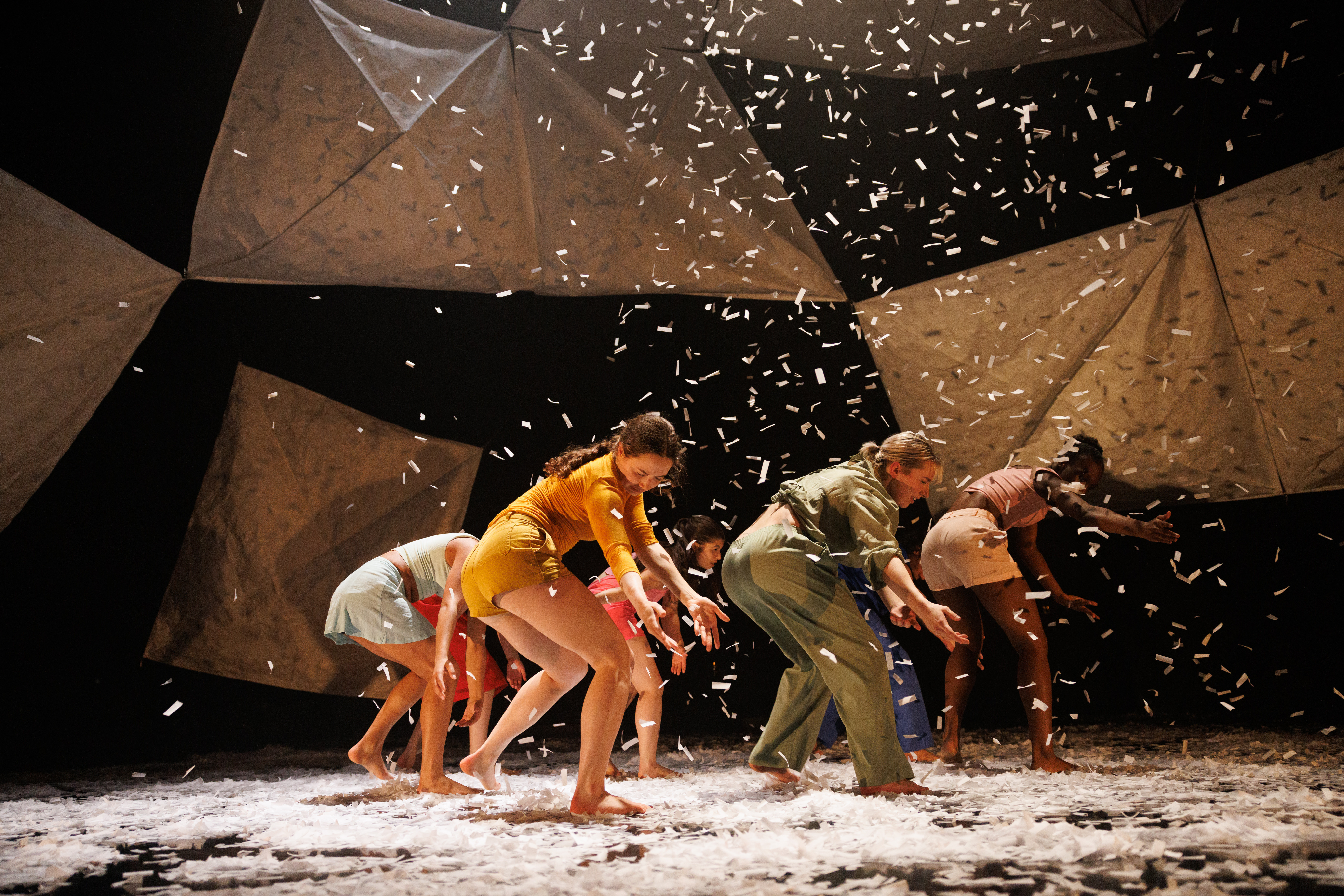 Dancers performing together as confetti falls all around them