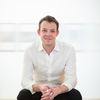 Person in a white shirt sitting against a light background.