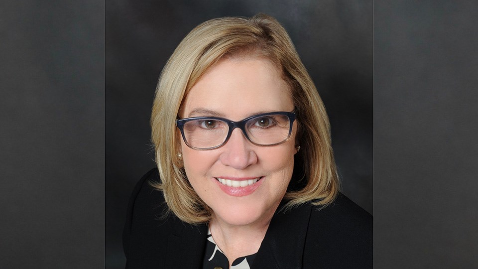 Headshot of Lori Husein with a dark background