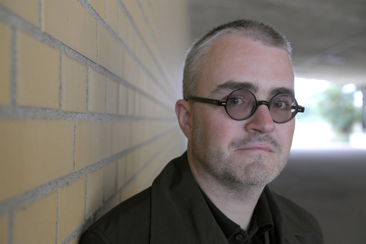 Headshot of Volker Straebel with a brick wall in the background