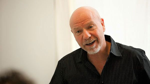 Headshot of Travis Preston in a black shirt giving a speech