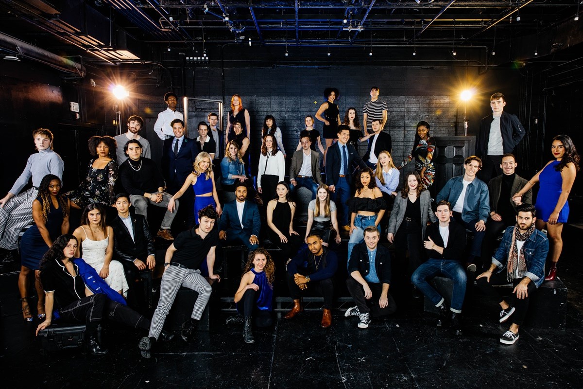 Group photo of people in a studio setting with stage lights.