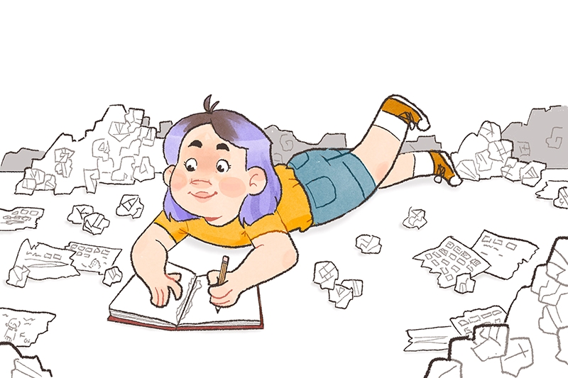 Girl lying on stomach drawing in a notebook, surrounded by crumpled papers.