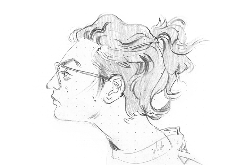 Pencil sketch of a person's head in profile, facing left with wavy hair tied in a loose bun and wearing glasses.