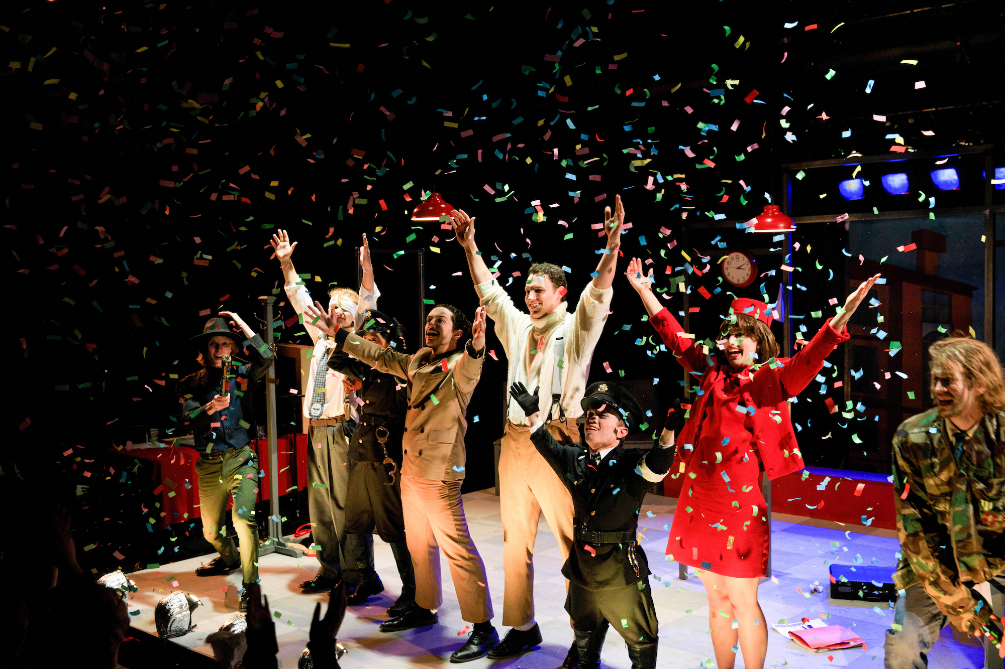 Student performers on stage bowing during curtain call while confetti rains down on them.