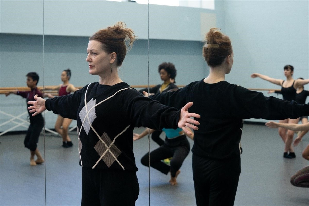 Dance instructor and students practicing in a mirrored studio.