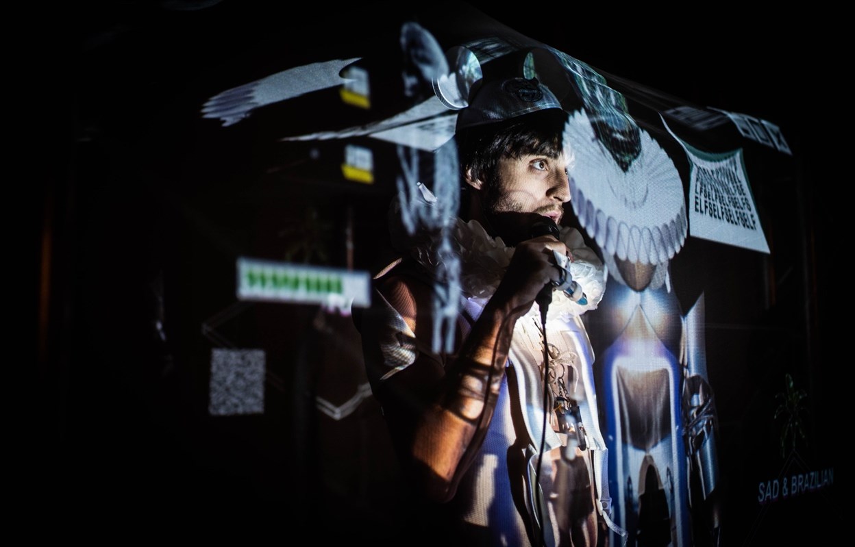 Man holding a microphone with colorful projections on him.