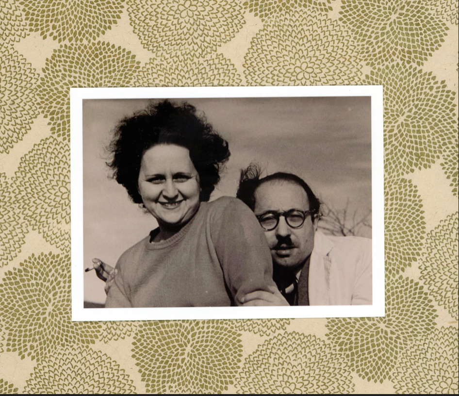 Black and white photo of a smiling woman with a man behind her, framed by a floral patterned border.