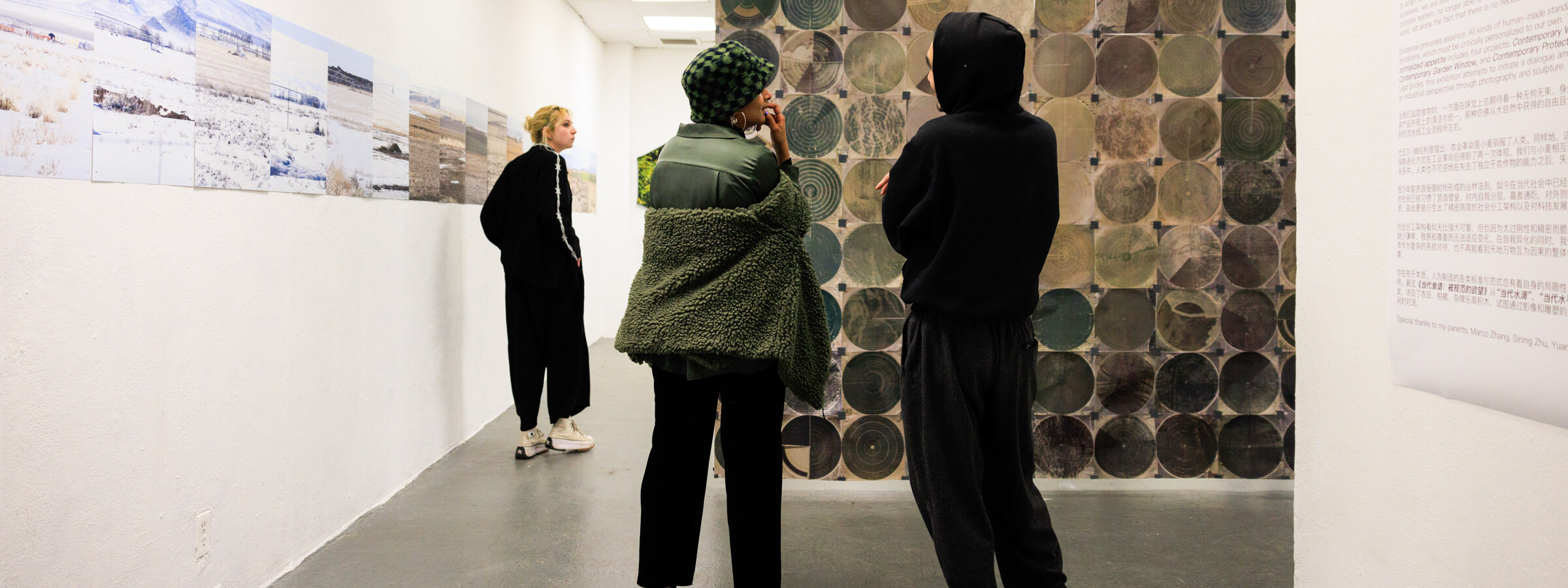 two people, seen from behind, discussing a large artwork composed of green and brown circles.