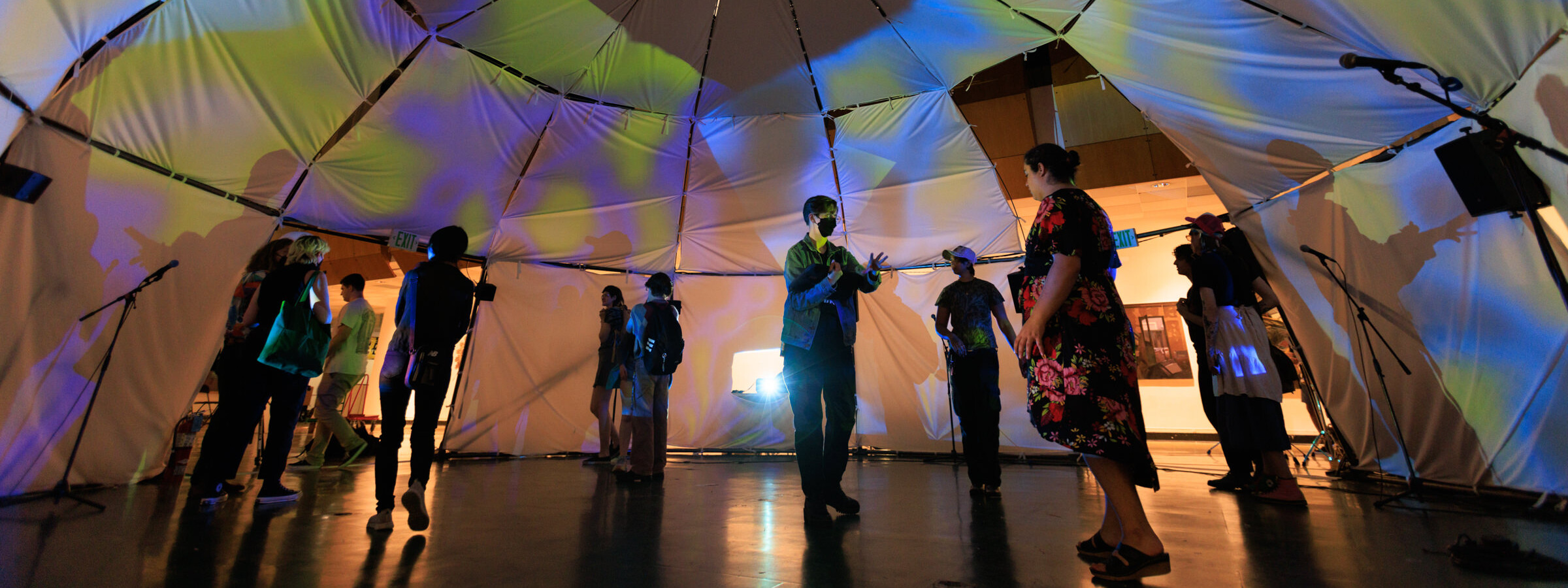 multiple figures stand inside a fabric dome, images are being projected on the white walls 