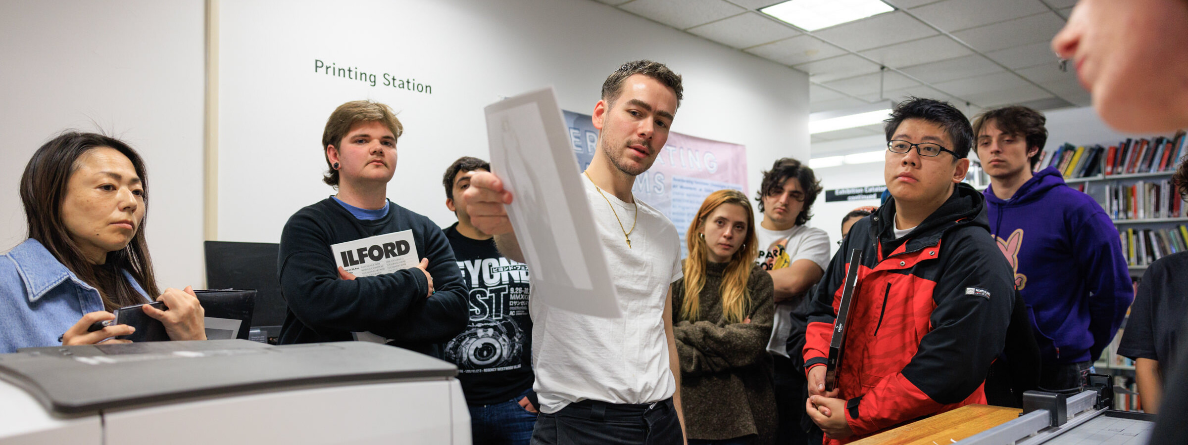 A man holds up an image for review by a group of people behind him.