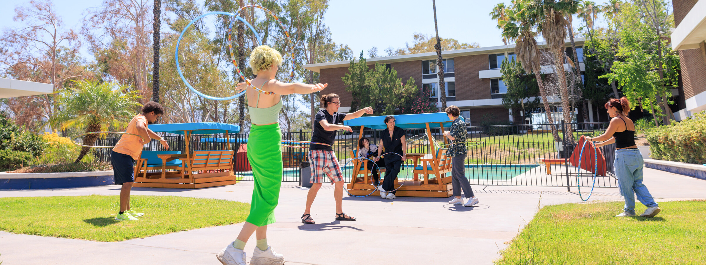 group of students at a dorm courtyard playing with hula hoops