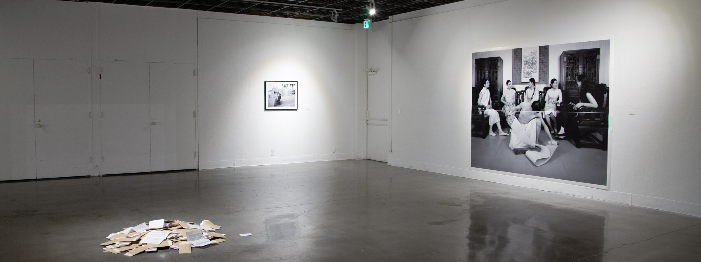 Photographic installation accompanied by a pile of books in the middle of the gallery. 