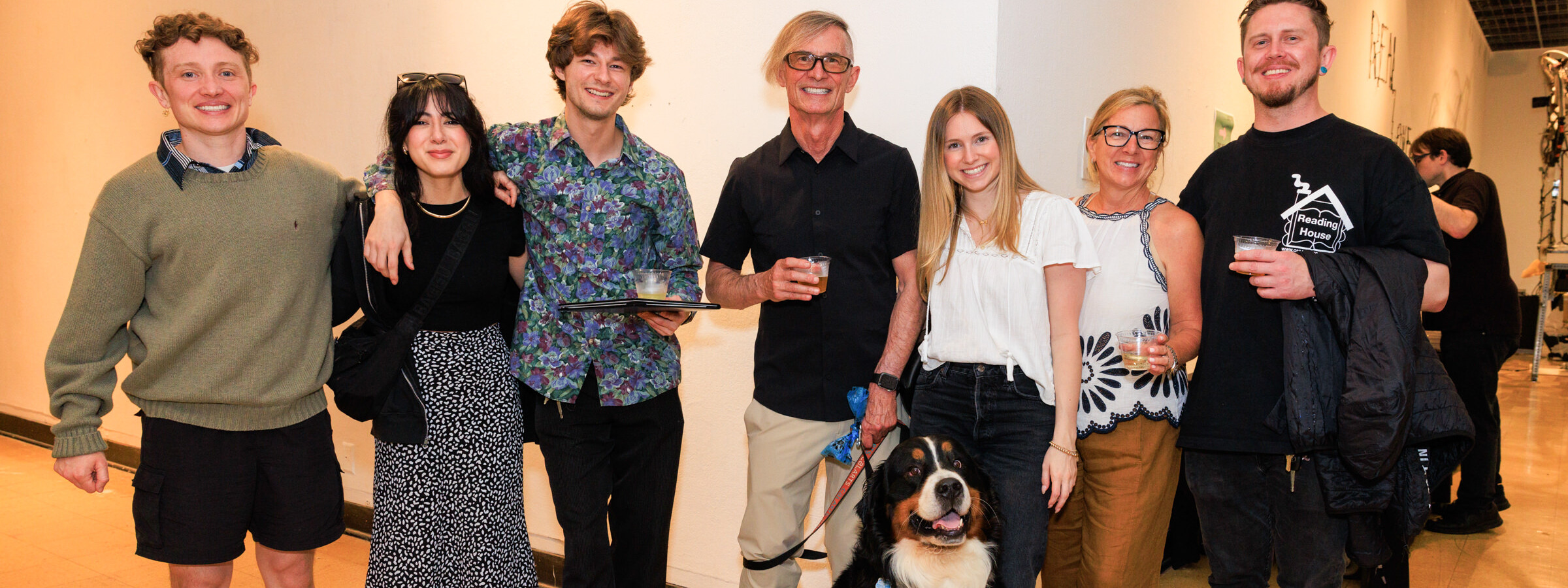 Group of seven people and a dog smile at a CalArts event.