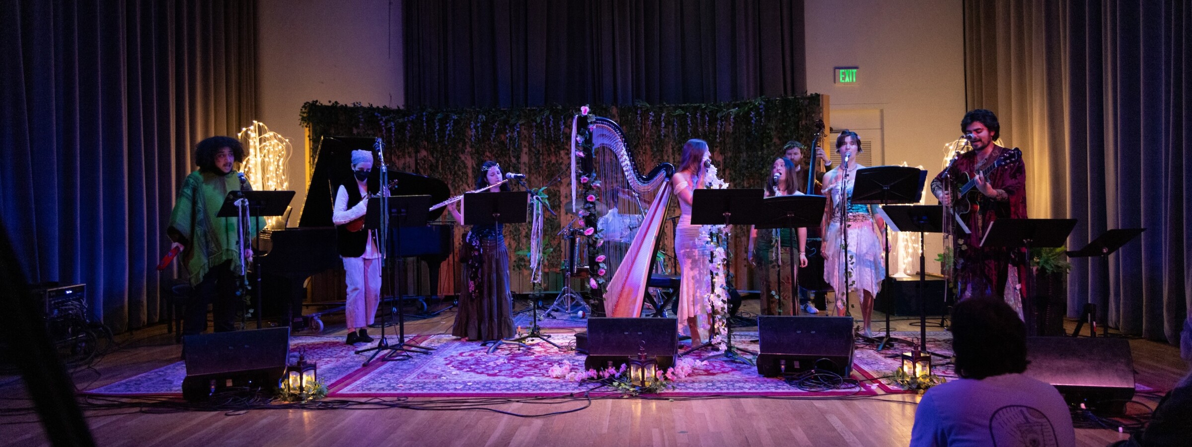 A woman in a white dress plays a harp on a stage