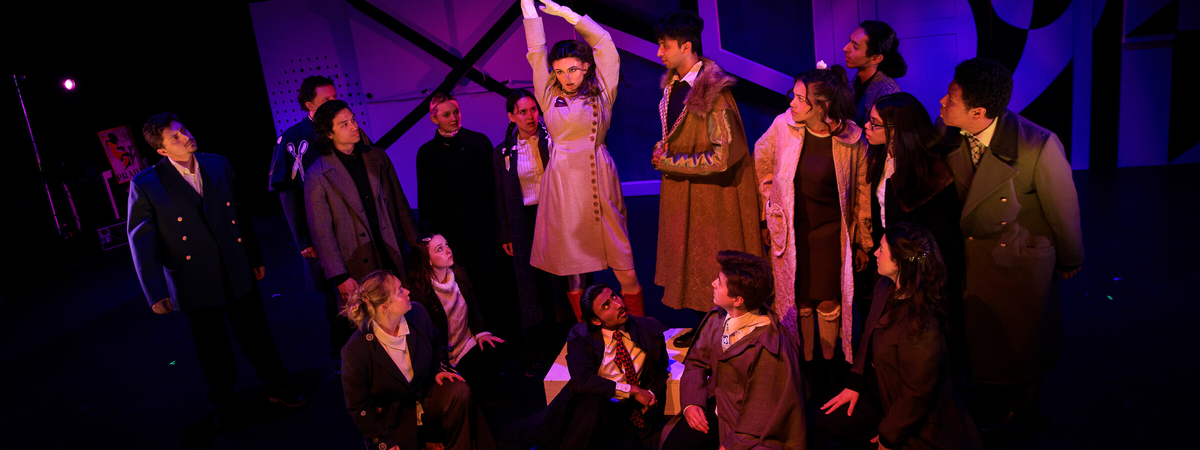 A group of people on a dimly lit theater stage focused on the person standing in the center