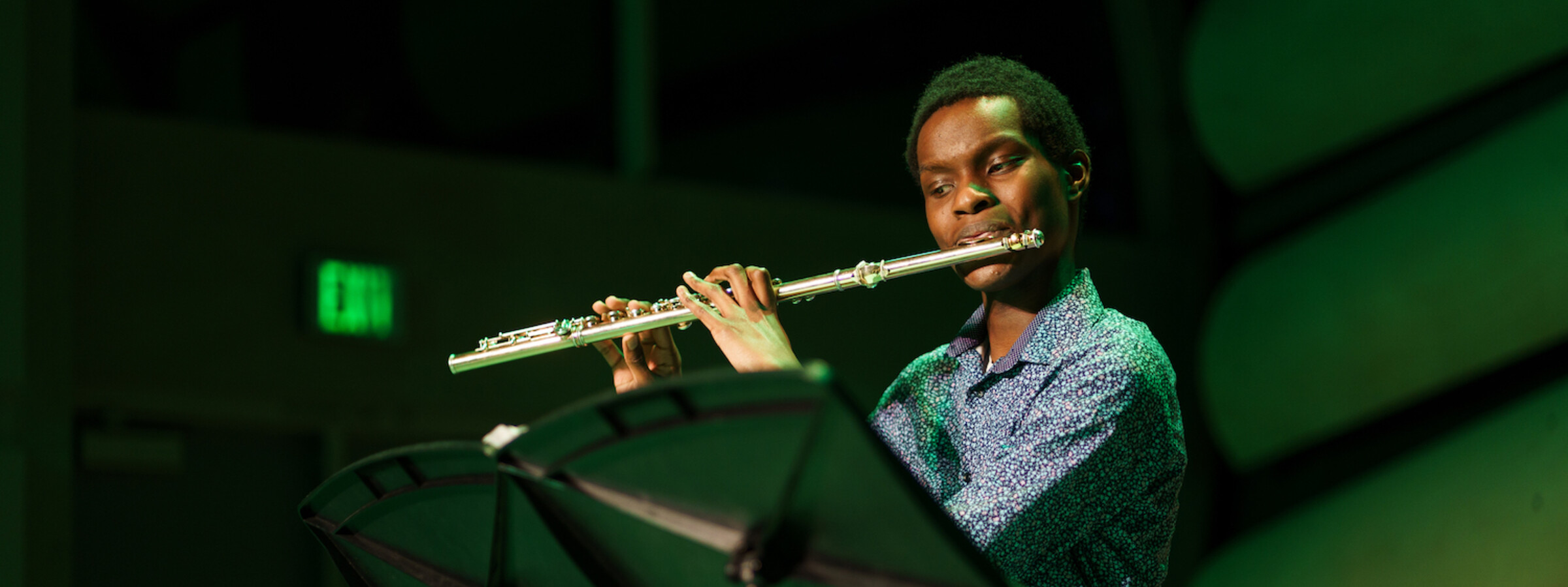 A person playing a flute on a dark stage