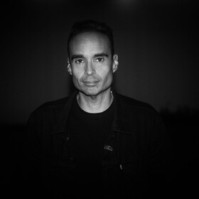 Photo of a man, John Tejada, in a dark room. 