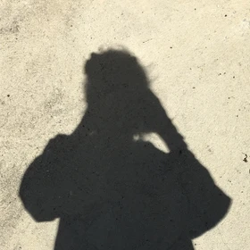 Shadow of a person on concrete with brown shoes visible.