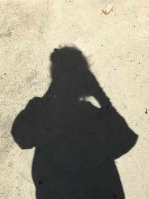 Shadow of a person on concrete with brown shoes visible.