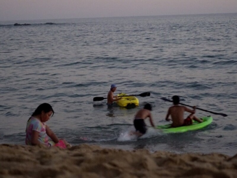 Image of several people playing on kayaks at a beach