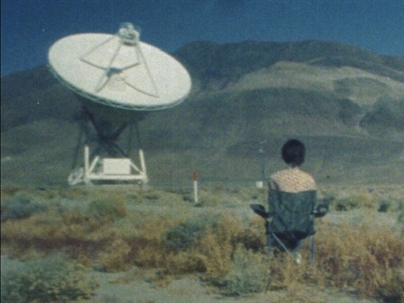 Image of a person sitting on a chair looking at a satellite dish