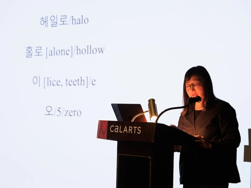A female speaker at a podium in front of a projected screen