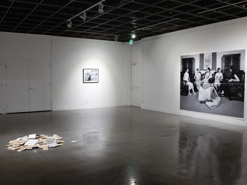 Photographic installation accompanied by a pile of books in the middle of the gallery. 