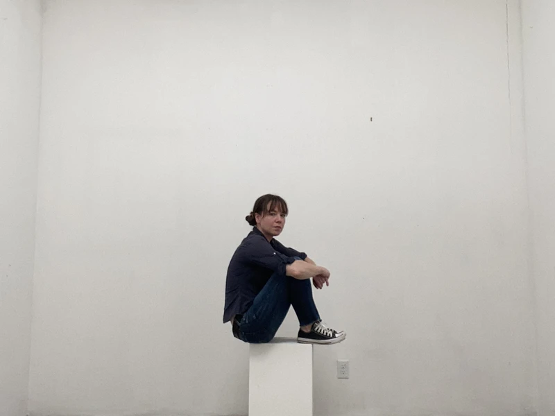 Amanda Bauer sitting on an elevated platform with a whie background