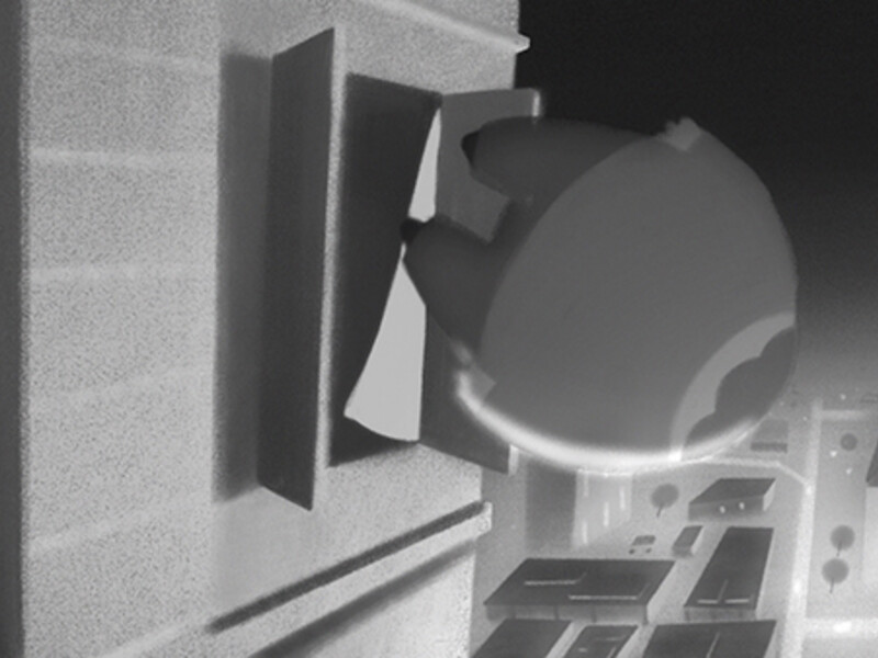  A cartoonish robot emerging from a window on a gray building against a grayscale cityscape.