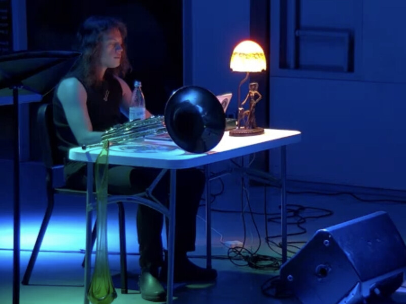 Nick Ginsburg working at a desk in a dark room, lit by a lamp and dim blue light