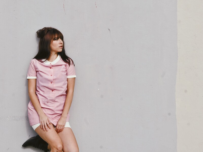 Taylor Donofrio posed in front of a large grey wall, wearing a dress