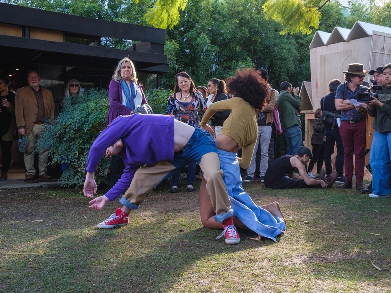 Two People Dancing Over Grass with Others Surrounding