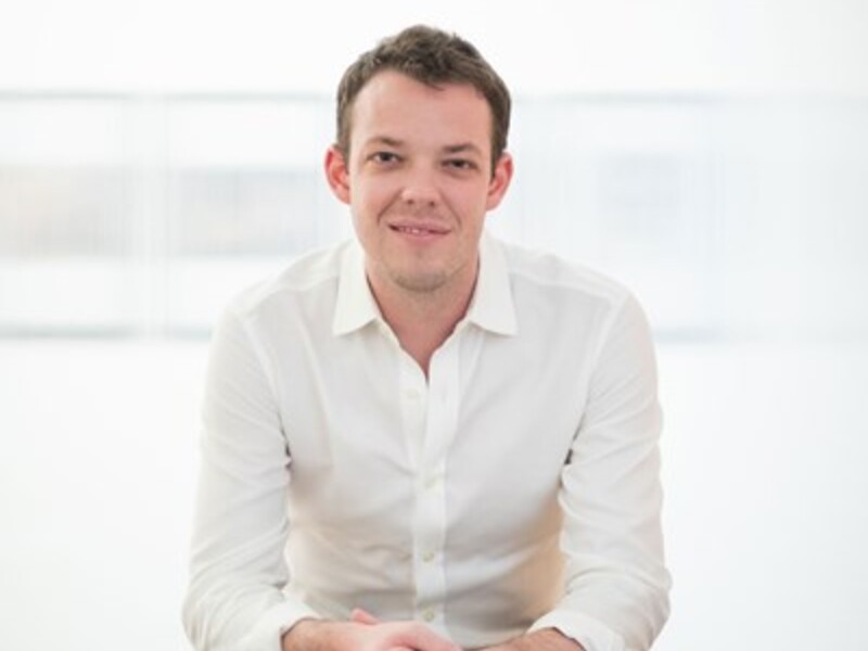 Person in a white shirt sitting against a light background.