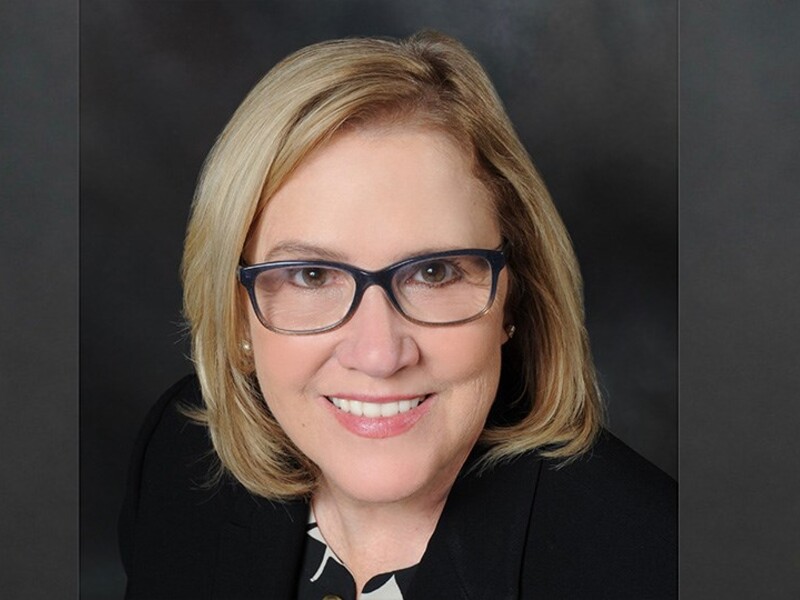 Headshot of Lori Husein with a dark background