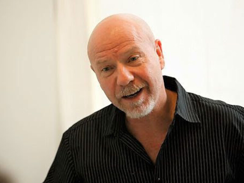 Headshot of Travis Preston in a black shirt giving a speech