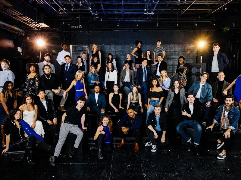 Group photo of people in a studio setting with stage lights.