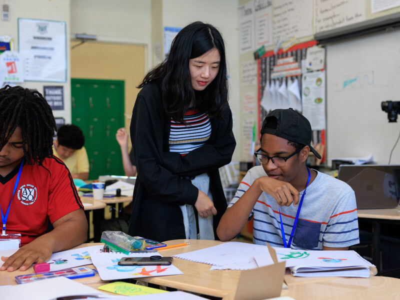 A CalArts' student-teacher works with CAP students on drawing.