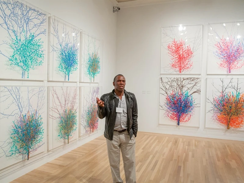 Art gallery with colorful tree-themed artworks and a person standing in front.