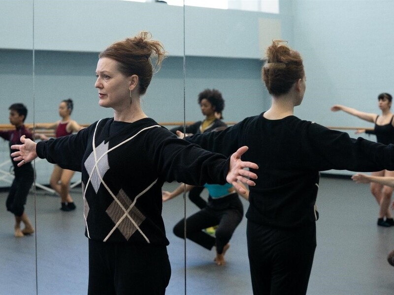 Dance instructor and students practicing in a mirrored studio.