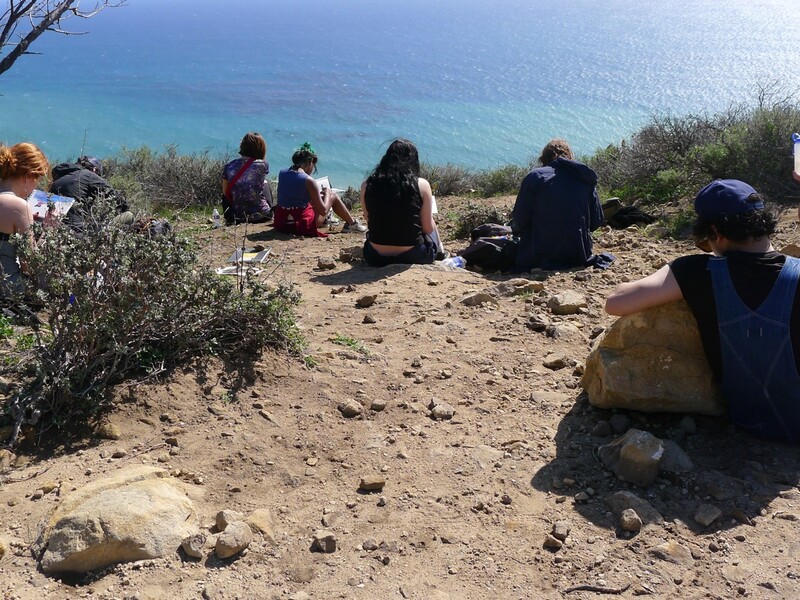 Expansive fields class at CalArts, featuring students drawing, seated on a rocky bluff facing the ocean