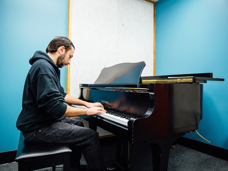 A person plays the piano in a small room with blue walls. 