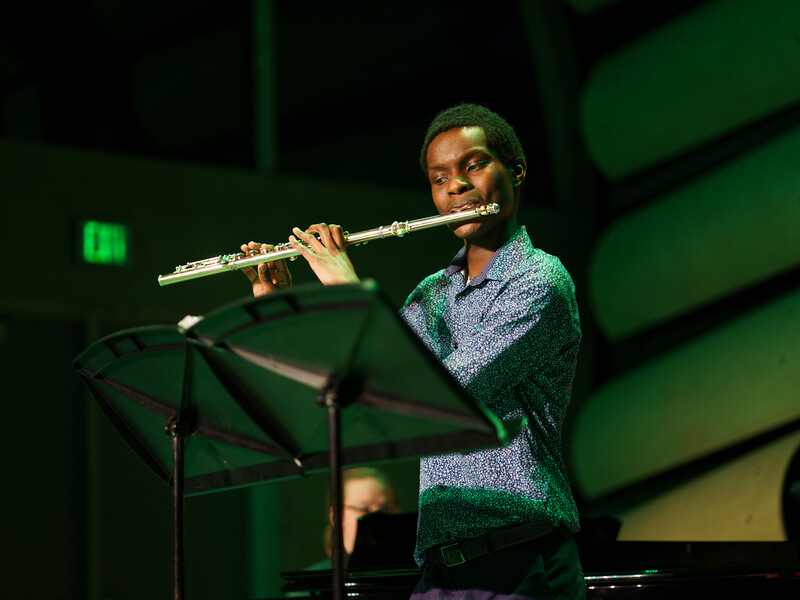 A person playing a flute on a dark stage