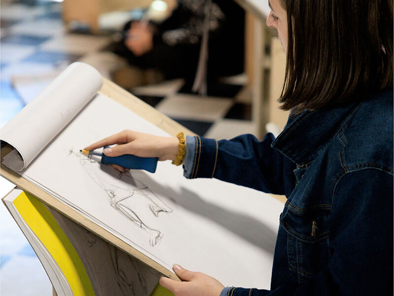 A student sketches in a large tablet sketchbook