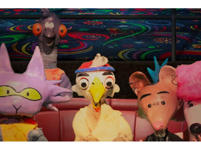 Puppet characters sitting in front of a colorful, psychedelic background.