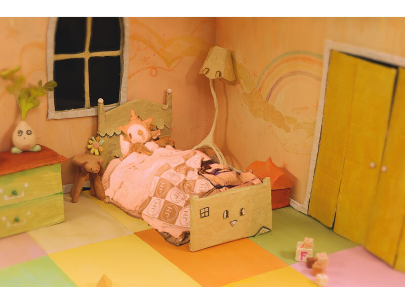 A miniature bedroom scene with a cute bed, pastel colors, and playful decorations.