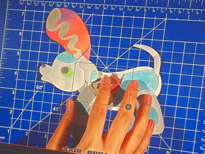 Colorful dog puzzle on a blue grid cutting mat with hands arranging the pieces.